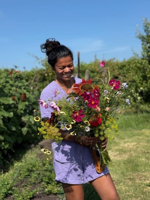 Vrijwilliger van Beemster Bloemen met een vers geplukt boeket in de tuin